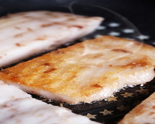 White fish fillet cooked in a pan with mixed vegetables